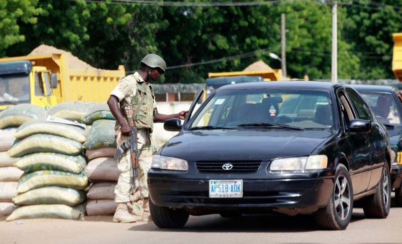 On the road: A soldier searches a car at a Maiduguri checkpoint, one of dozens guarding routes into the city