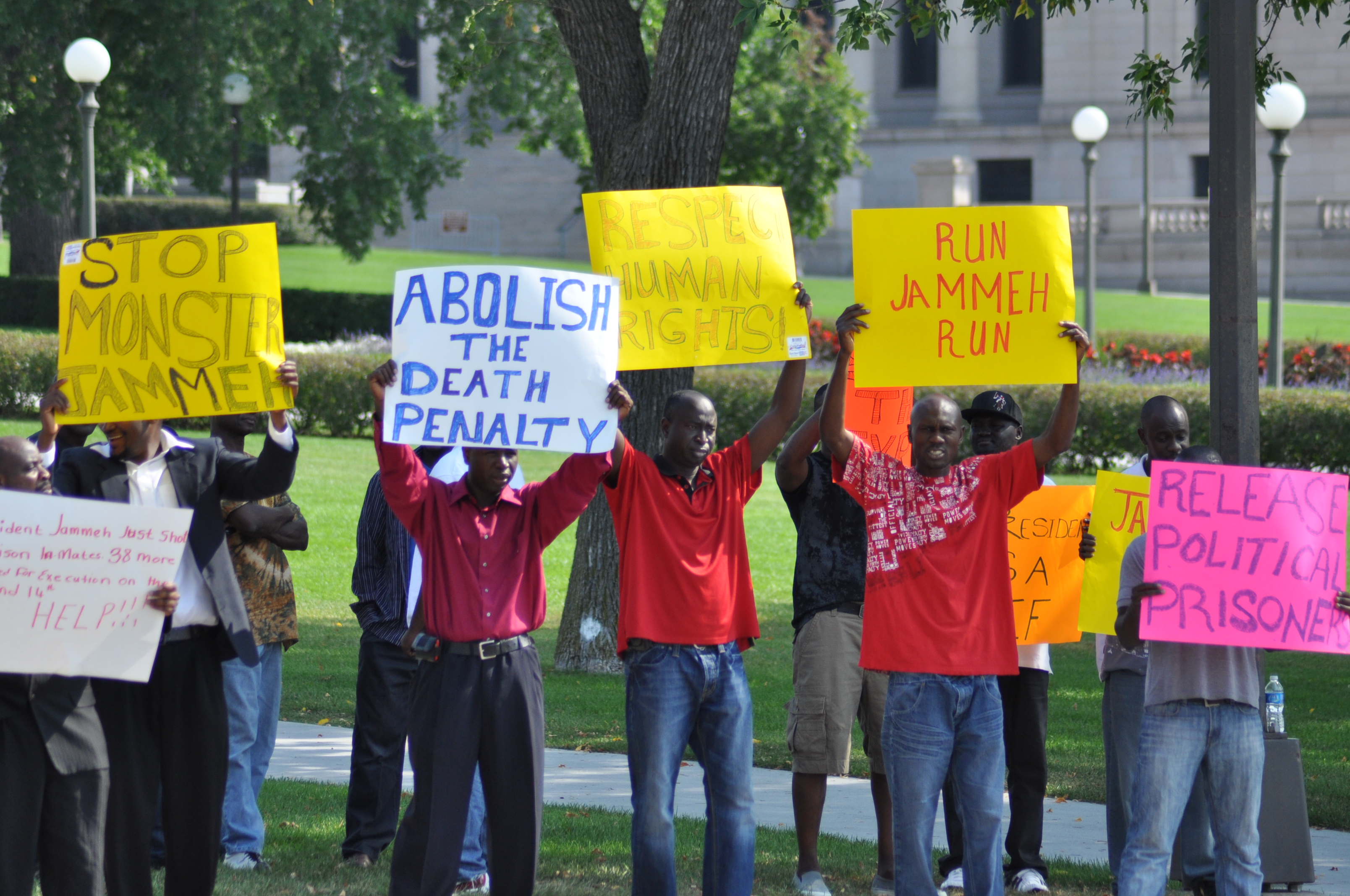 Group of people holding protest signs advocating for human rights and the abolition of the death penalty outdoors.