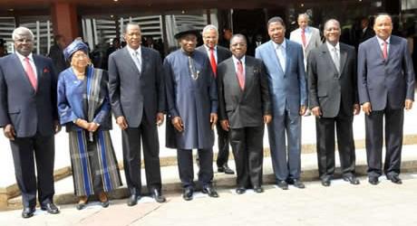 Group of eight african leaders and dignitaries standing together outside a building, dressed in formal attire.