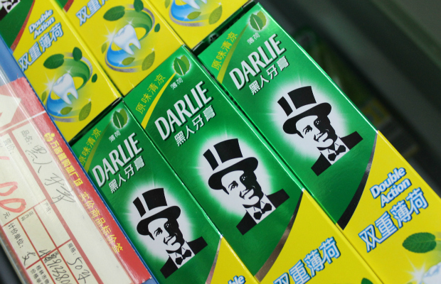 Boxes of darlie toothpaste, featuring a logo with a man in a top hat, lined up on a store shelf.