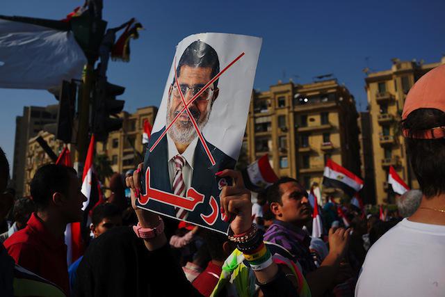 A man holding up a sign with an image of president morsi.