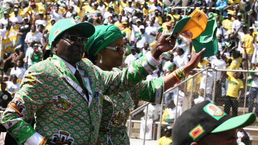 Two people in green and white suits holding a yellow hat.