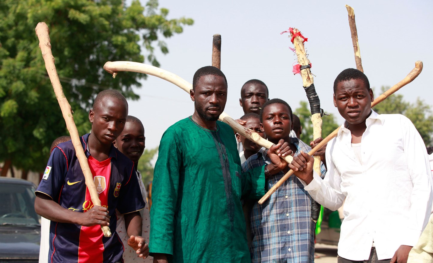 A group of men holding up wooden sticks.