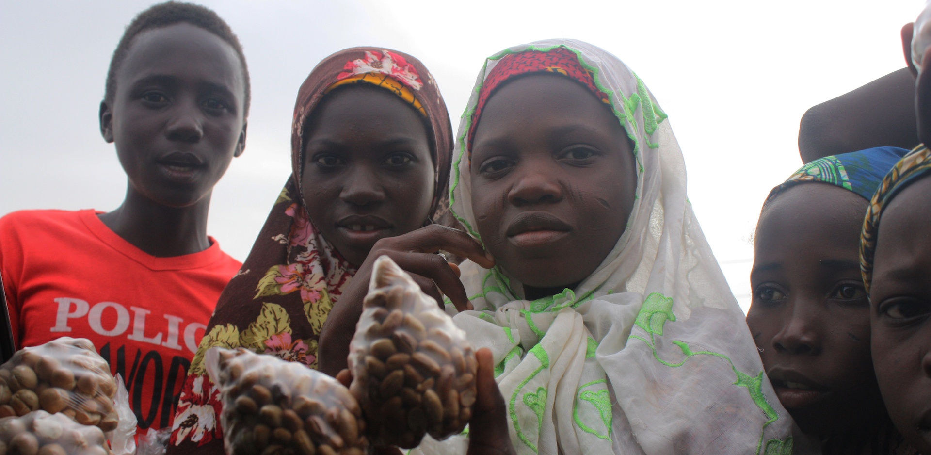 Two women in headscarves holding a bunch of food.