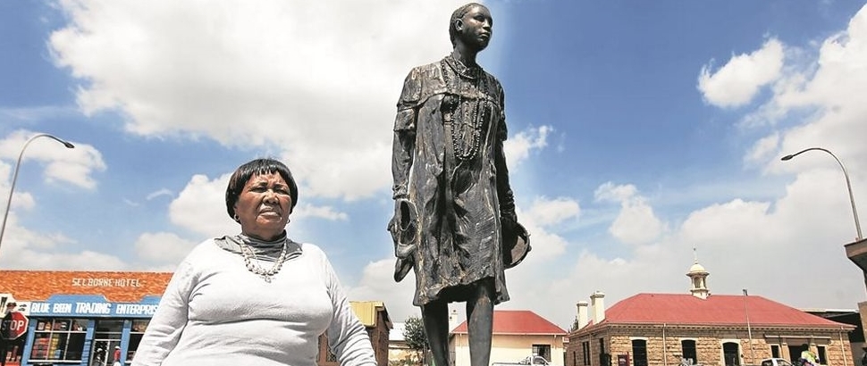 A woman standing next to a statue of a man.