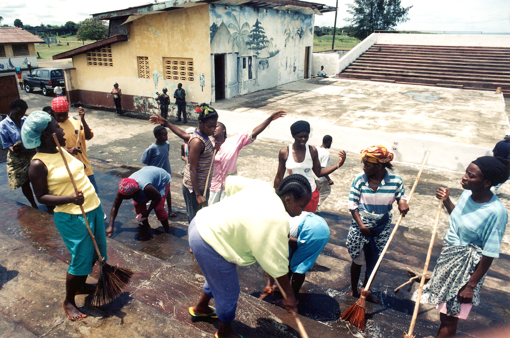 A group of people sweeping the ground with brooms.