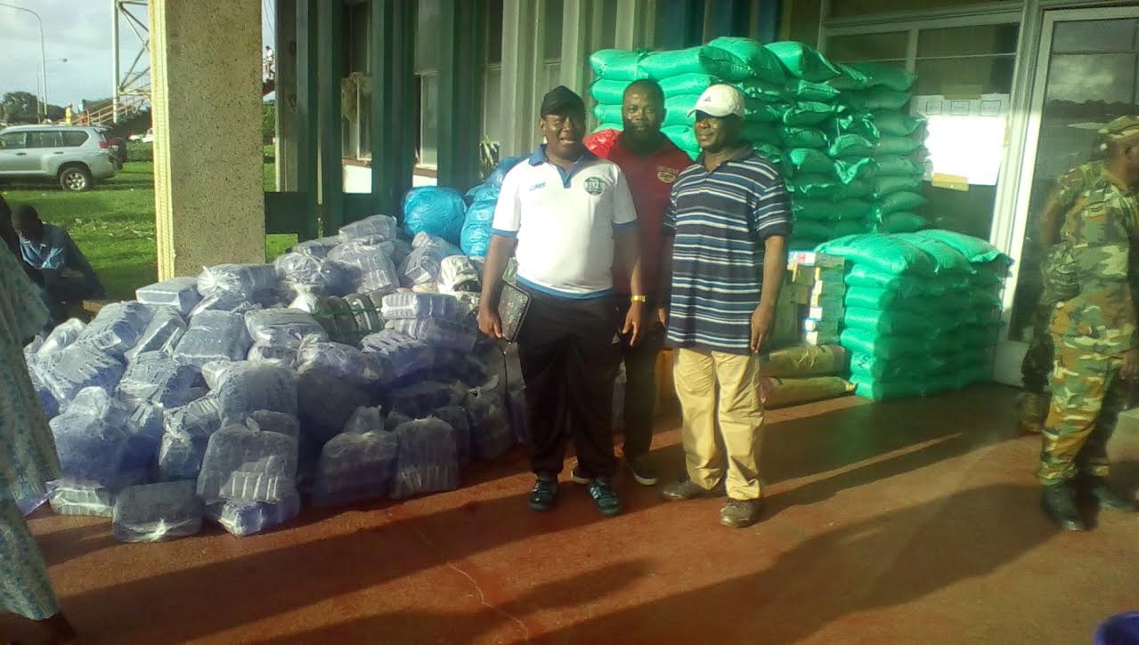 Three men standing in front of a pile of bags.