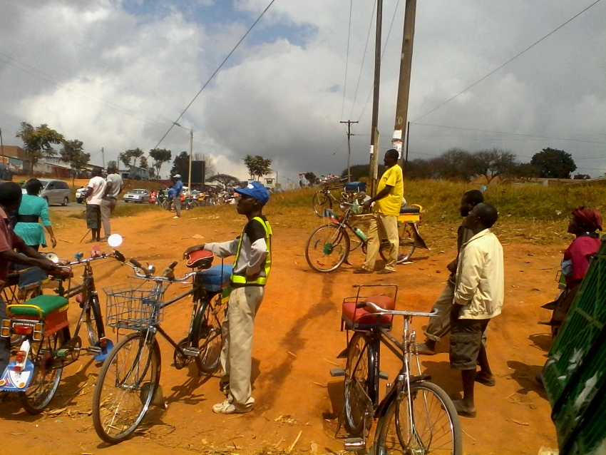 A group of people standing around bicycles on dirt.