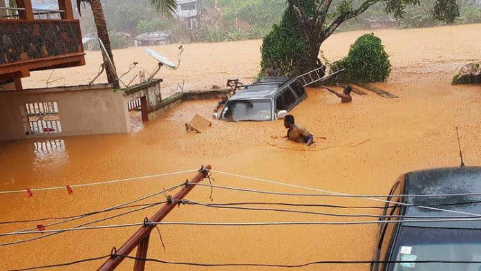 A car is submerged in the water of a flooded area.