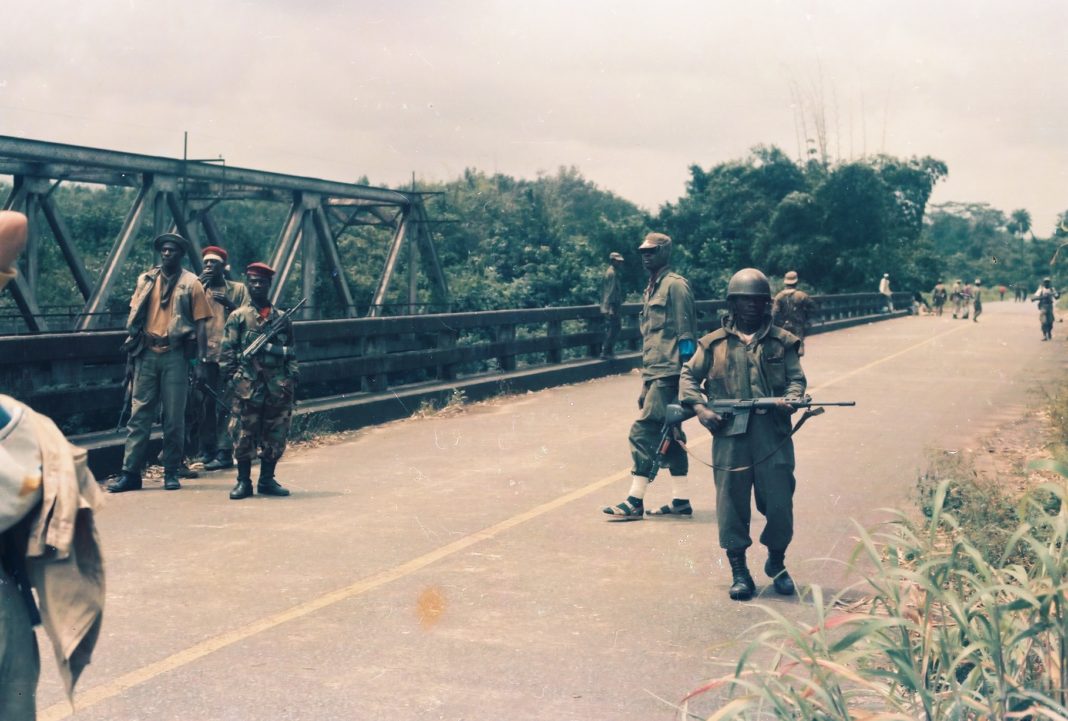 A group of soldiers standing on the side of a road.