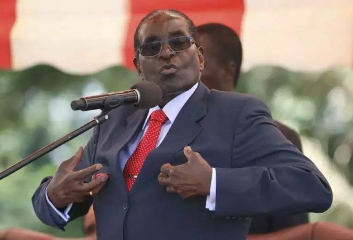 A man in a suit and red tie is speaking into a microphone.