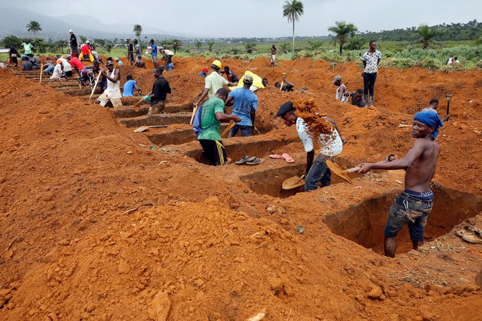 Workers are seen digging graves at Paloko cemetery in Waterloo, Sierra Leone August 17, 2017. Credit: REUTERS/Afolabi Sotunde A group of people digging in the ground.