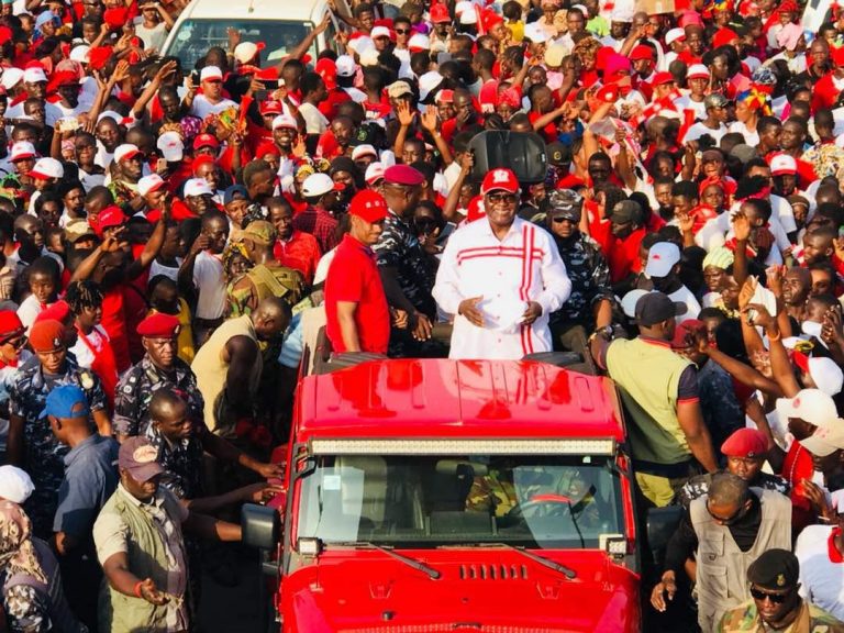A large crowd of people are gathered around a red truck.