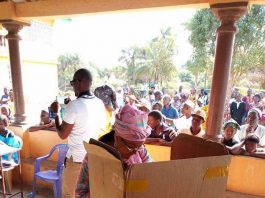 A woman in a box is standing next to a crowd.