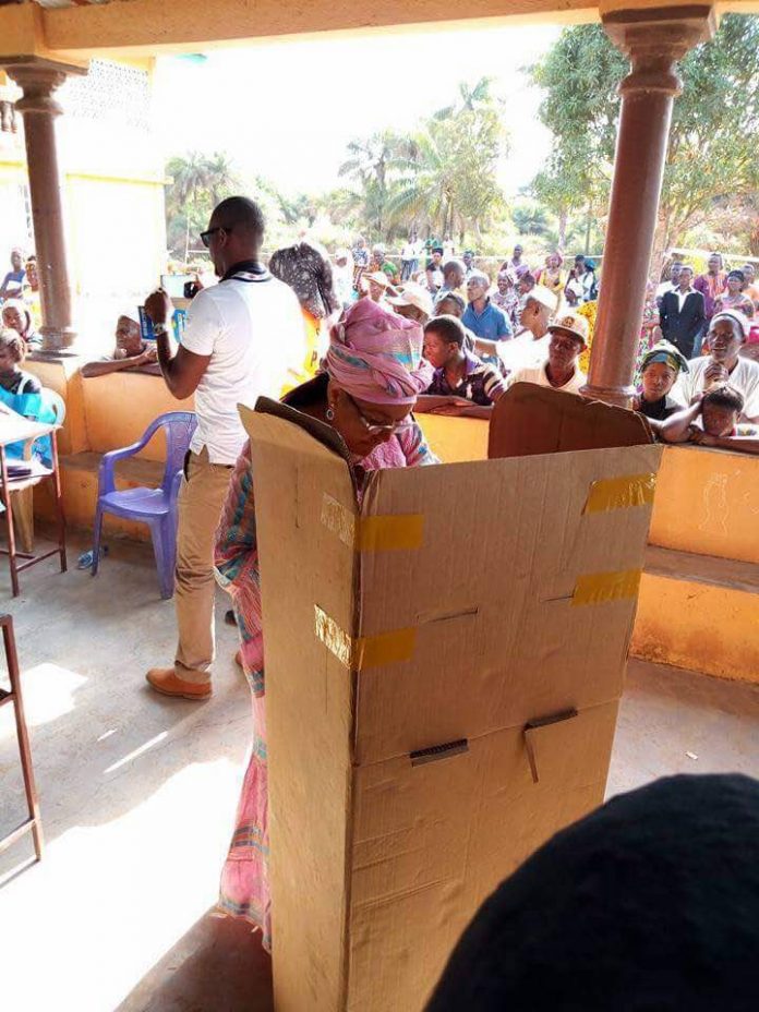 A woman in a box is standing next to a crowd.