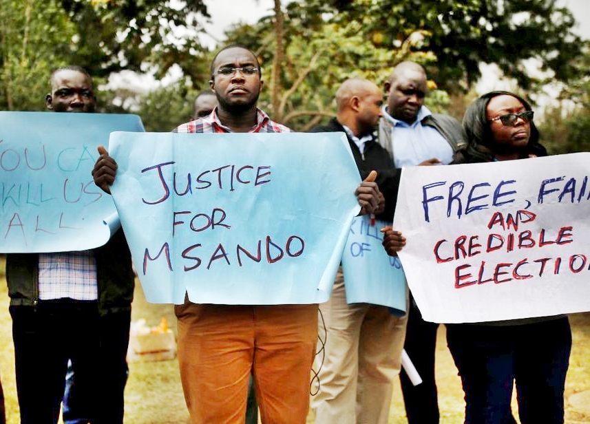 Residents from late Msando village carry placards in protest of unfinished probe investigations