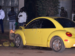 A yellow car that has been smashed by a man.