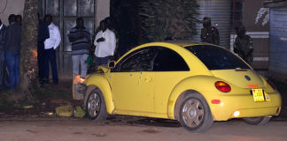 A yellow car that has been smashed by a man.