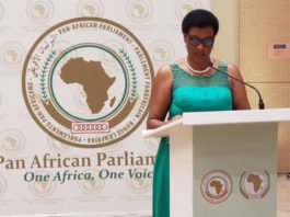 A woman in green dress speaking at podium.