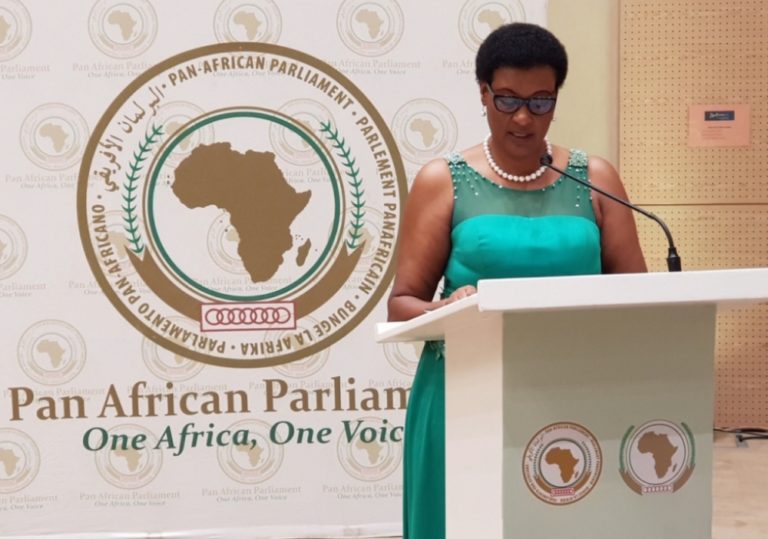 A woman in green dress speaking at podium.