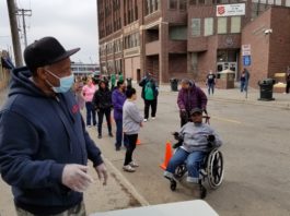 A man in a wheelchair and some people on the sidewalk