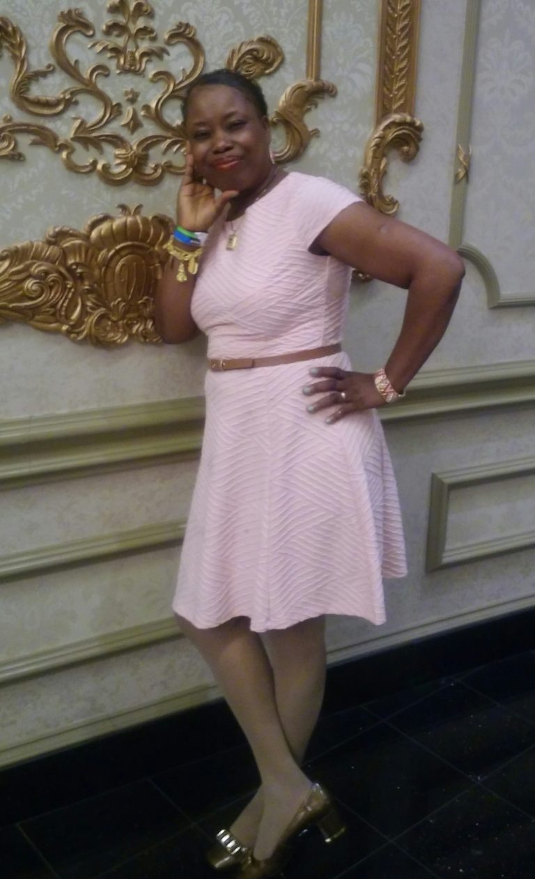 A woman in a pink dress posing for the camera.