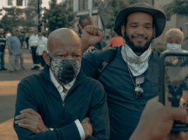 Two men in masks are standing together on the street.