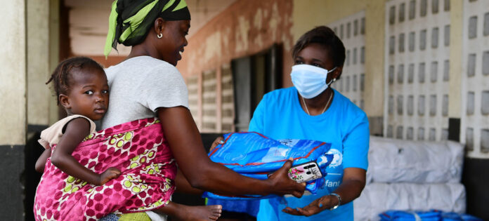 A woman in blue shirt holding up a bag.
